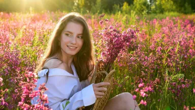 Девушка на лугу с букетом полевых цветов